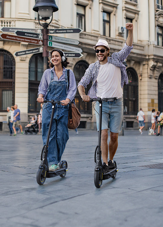 a man and a woman happily riding engwe y10 e-scooter on the road