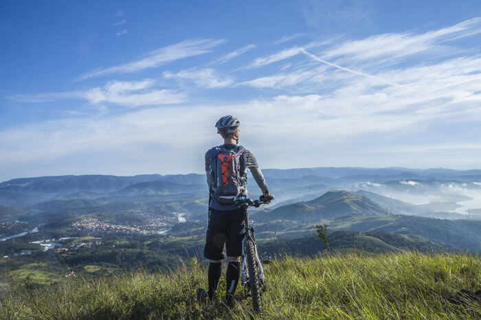 a man hoding a bike on the top of mountain