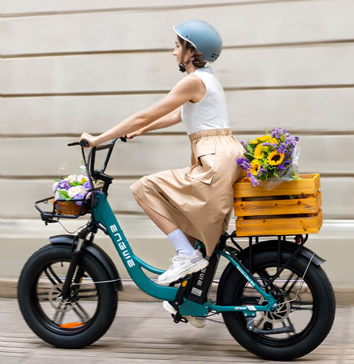 a woman wearing a helmet rides a green engwe l20 boost e-bike on the street