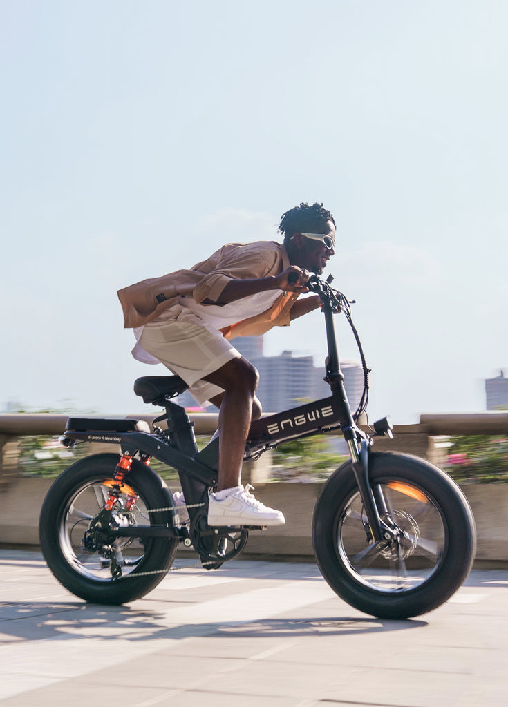 a man rides a black engwe x20 fold up electric bike on the road